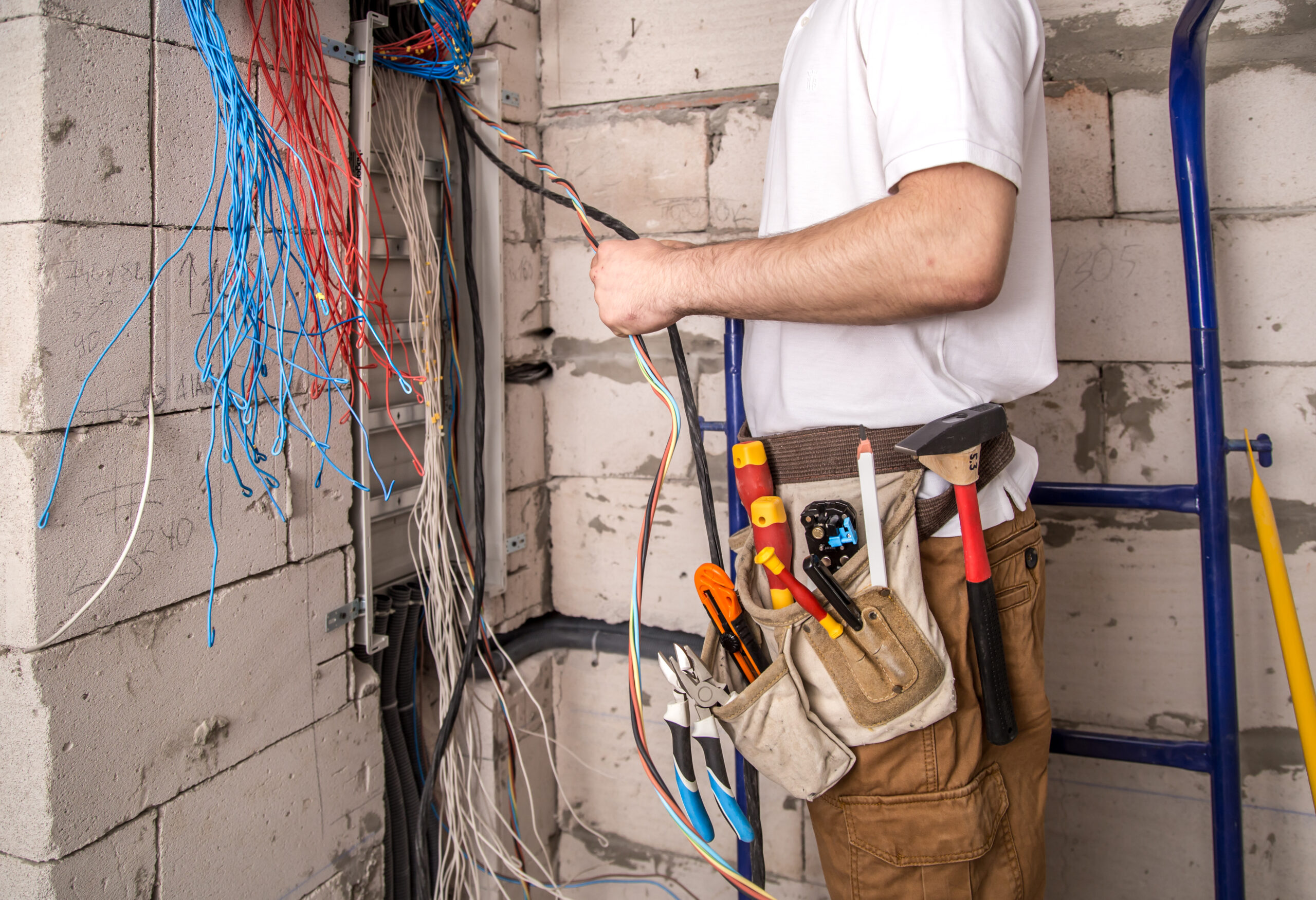 Electrician working near the Board with wires. Installation and connection of electrics.